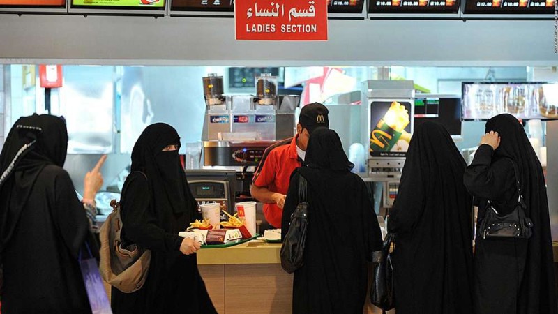 Women shrouded in black niqabs at the ladies counter in a fast-food joint.